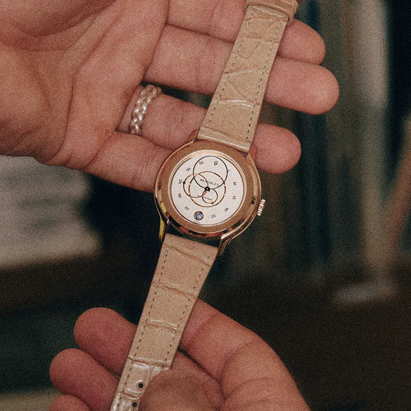 Montre Beaubleu Ecce Lys tenue entre deux mains avec le bracelet Flat White en cuir d’alligator couleur crème