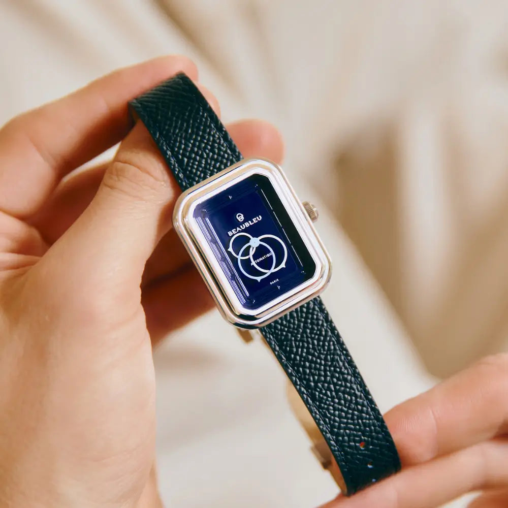 Montre Ecce Figura Smalt au cadran bleu, tenue entre deux doigts, avec un bracelet en cuir bleu grainé