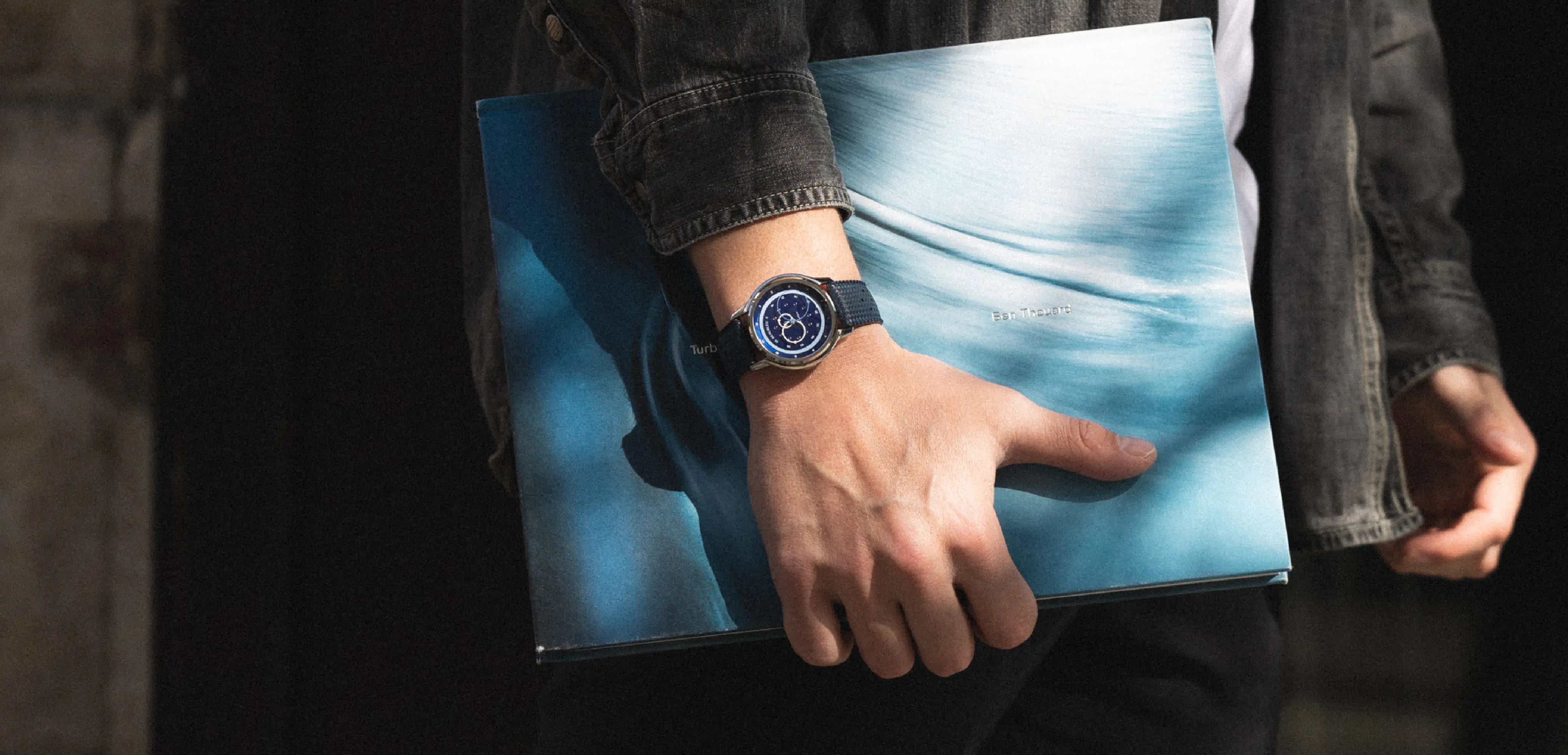 GMT bleue au poignet en tenant un livre