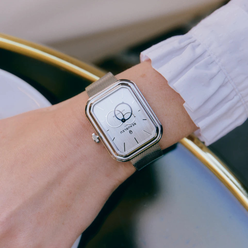 Ecce Figura Vesperal portée au poignet d'une femme dont la main est posée sur une table de café