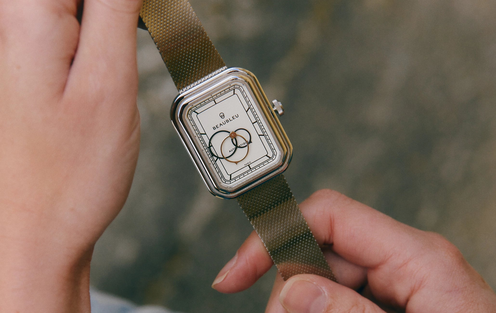 Montre automatique Ecce Figura Alba tenue entre deux mains, cadran visible en gros plan