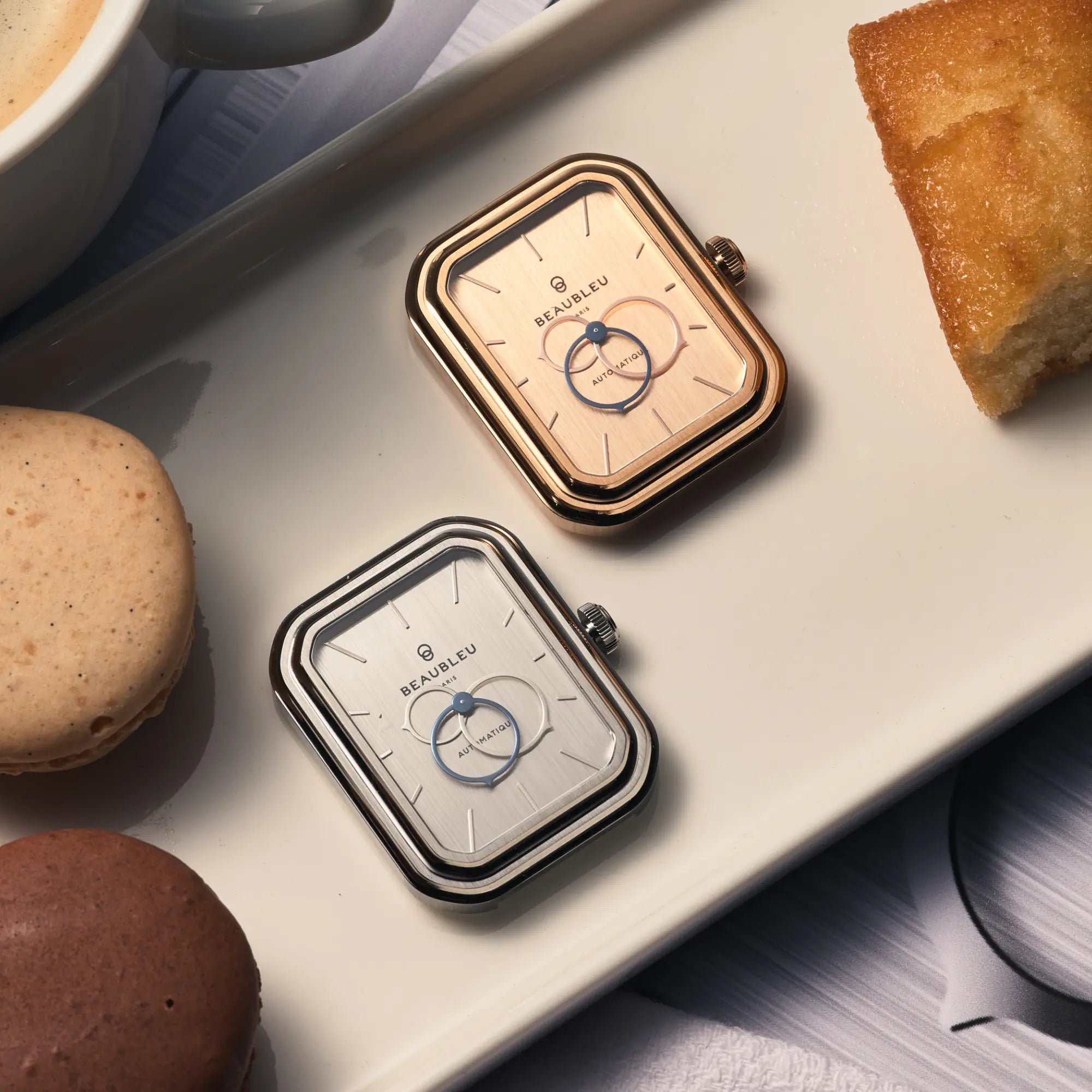 Deux boîtiers de montre en acier brossé posés côte à côte : un en acier et l’autre en or rose