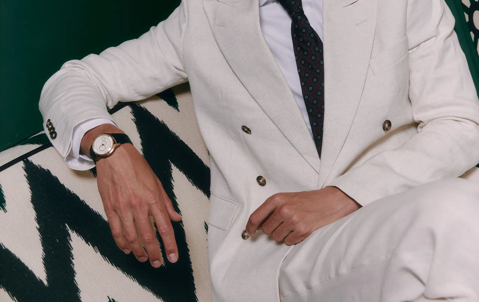 Montre Beaubleu La Pièce Champagne à bracelet en cuir noir grainé portée par un homme en costume blanc assis sur un canapé