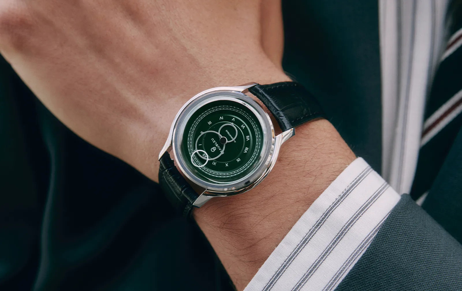 Gros plan sur la montre La Pièce Vert Olive de Beaubleu portée avec une chemise à rayures et un costume bleu