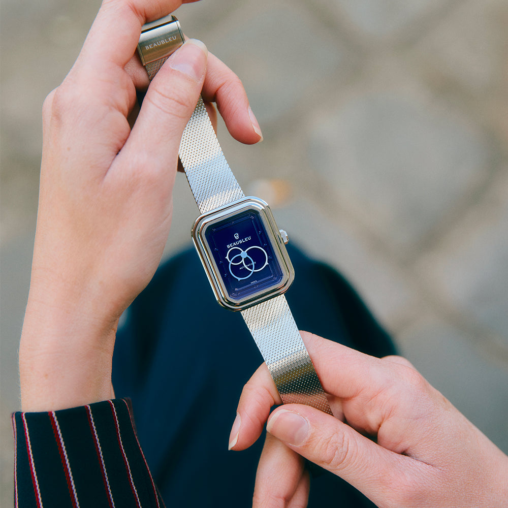 Gros plan de mains tenant une montre Beaubleu Figura Smalt avec bracelet en métal