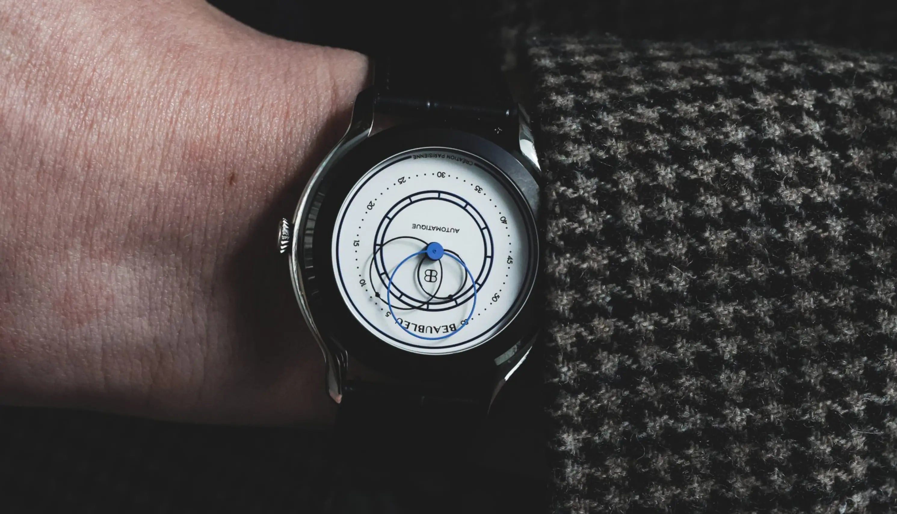 Montre Union au poignet d'un homme veste pied de poule