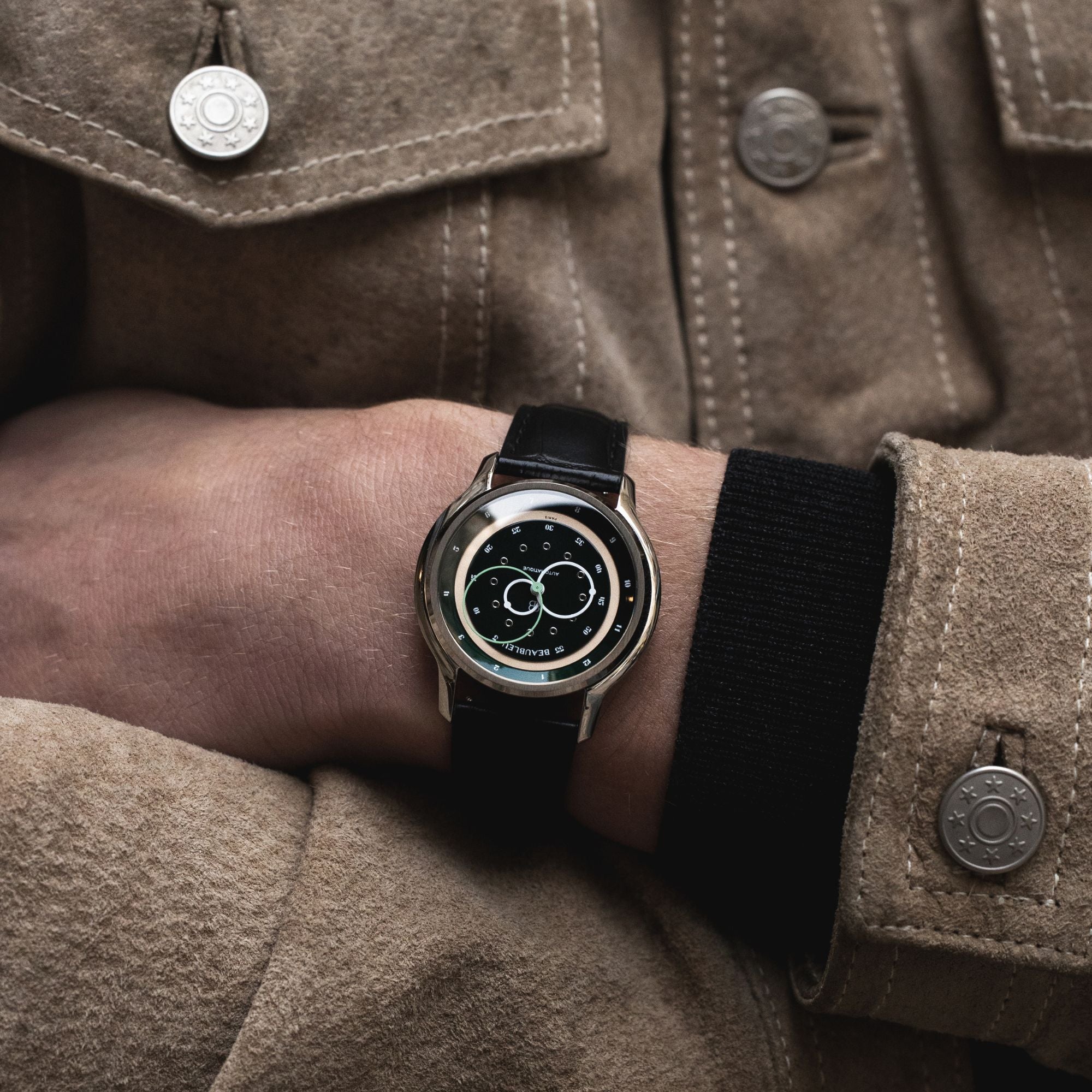 Montre GMT Verte avec un bracelet en cuir noir portée au poignet d'un homme