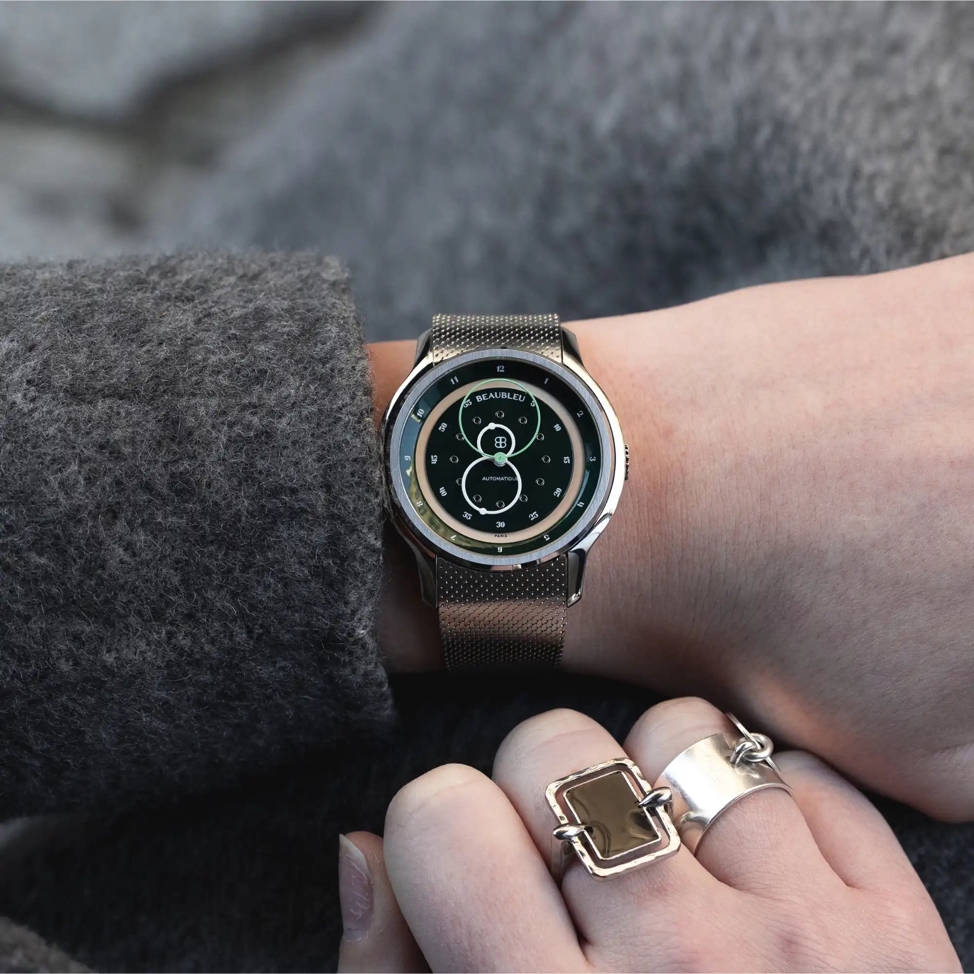 Montre GMT verte sur bracelet en acier, portée au poignet d'une femme