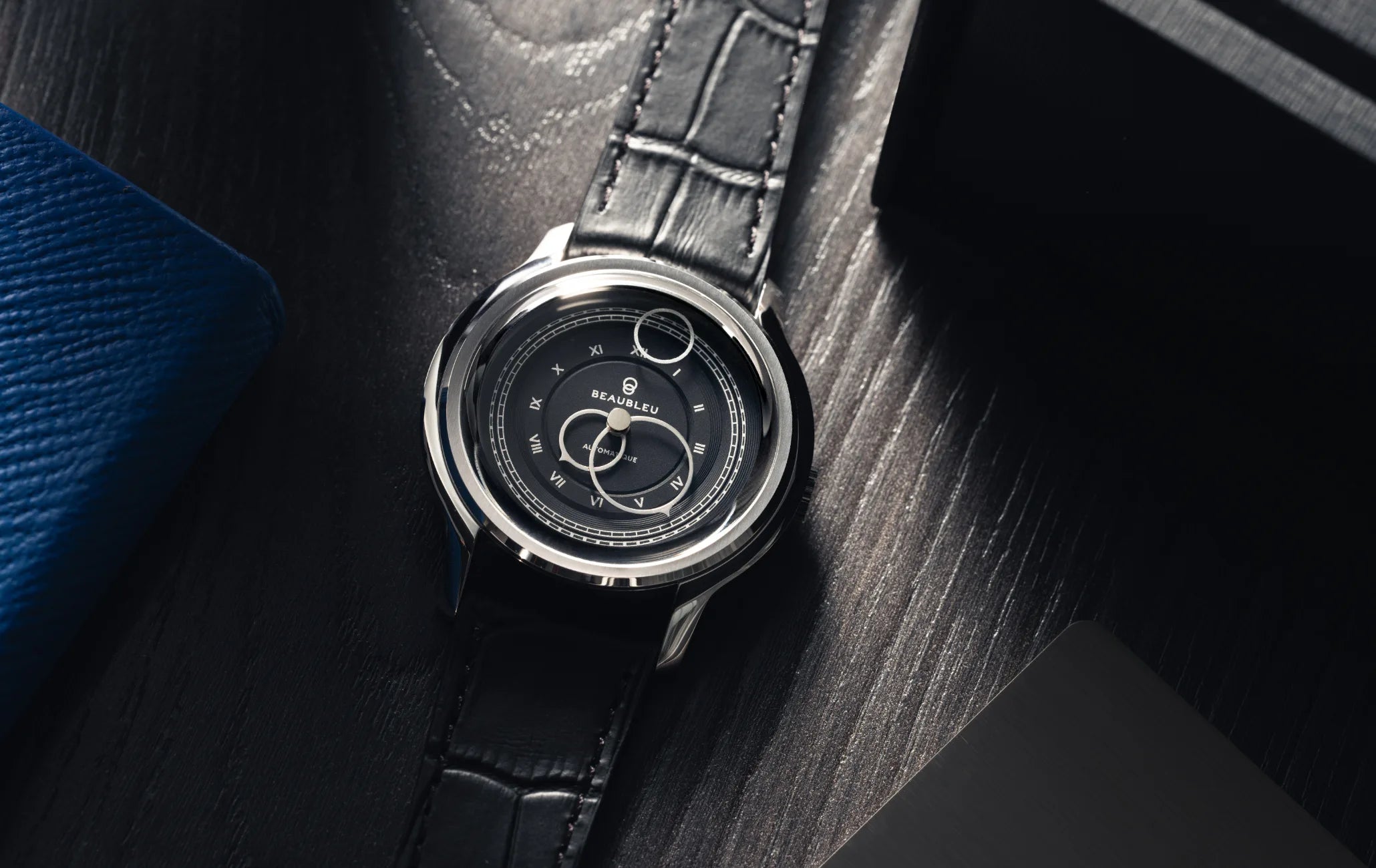 Montre La Pièce Graphite de Beaubleu cadran gris posée sur une table en bois