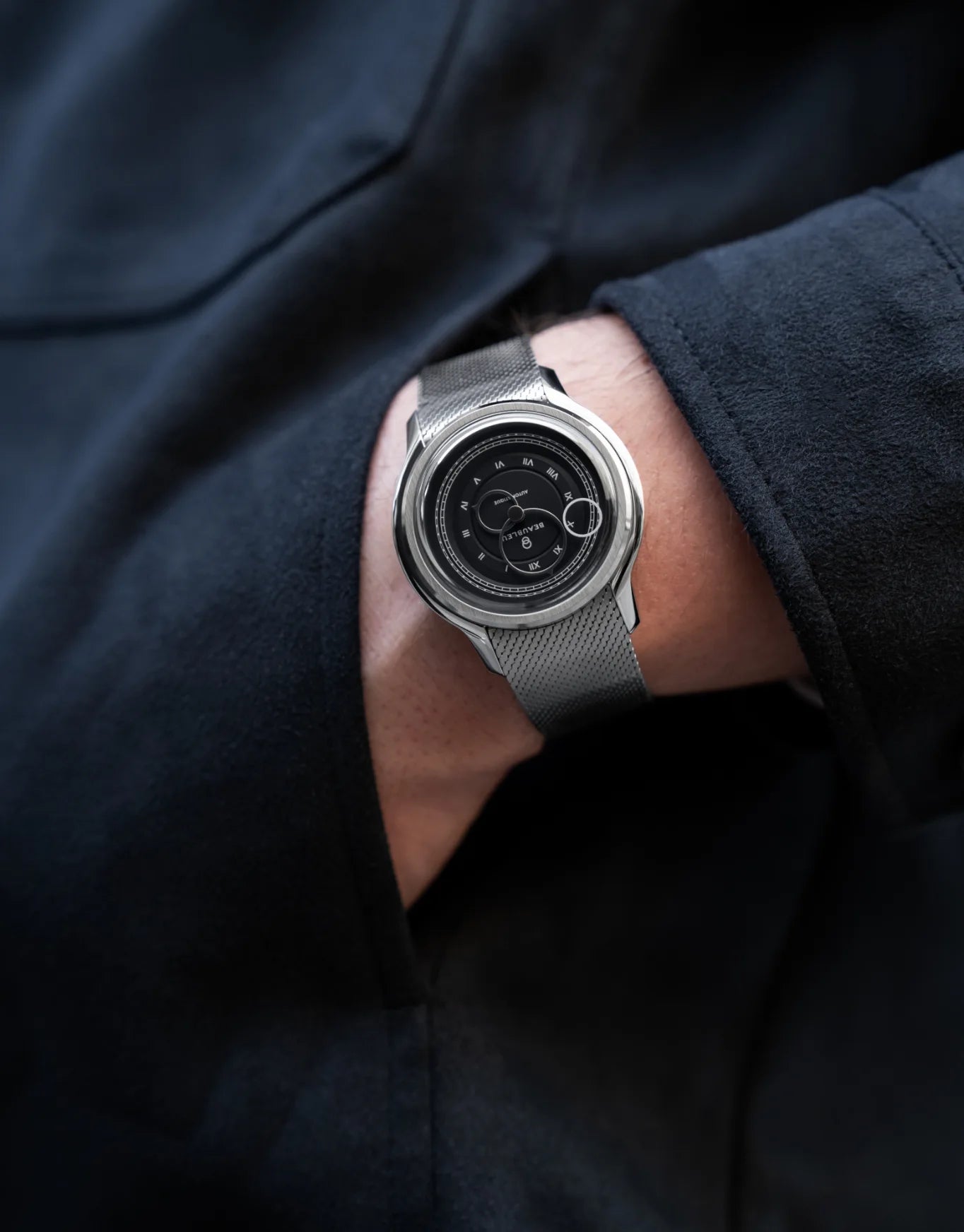 Main dans la poche avec au poignet une montre Beaubleu La Pièce Graphite et un bracelet acier
