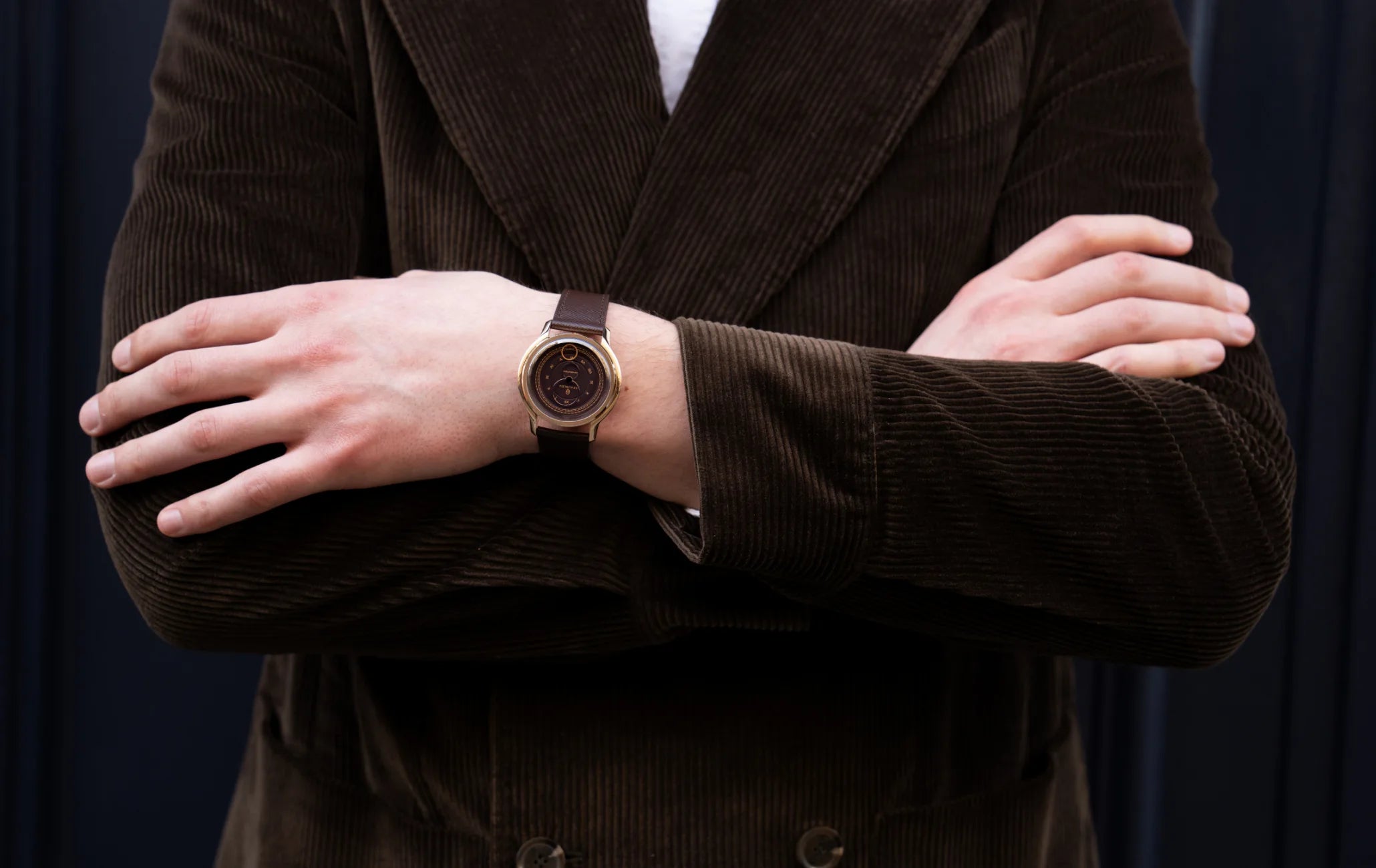 Montre Beaubleu La Pièce Moka avec bracelet cuir grainé portée au poignet d'un homme avec une veste de costume marron