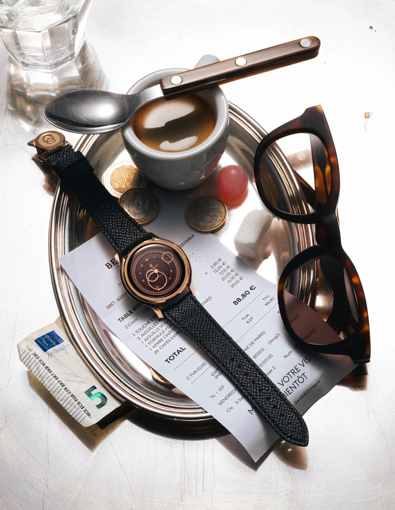 Montre La Pièce Moka de Beaubleu posée sur plateau en argent avec autour plusieurs accessoires