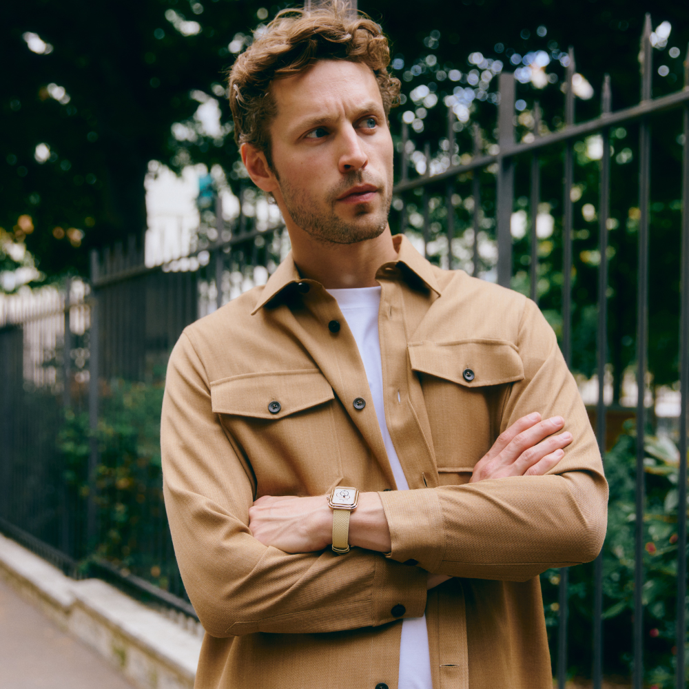 Homme debout les bras croisés portant une Ecce Figura Lys avec bracelet crème grainé