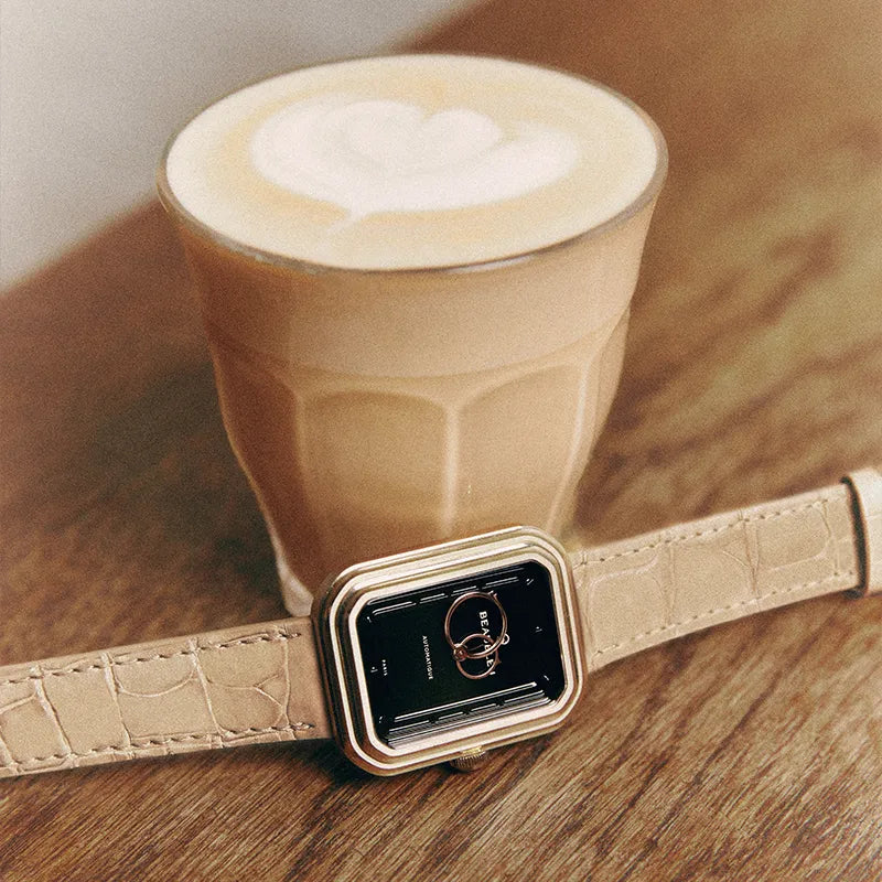 Montre Beaubleu Ecce Figura Onyx avec bracelet Flat White en cuir d’alligator crème, près d’un café latte