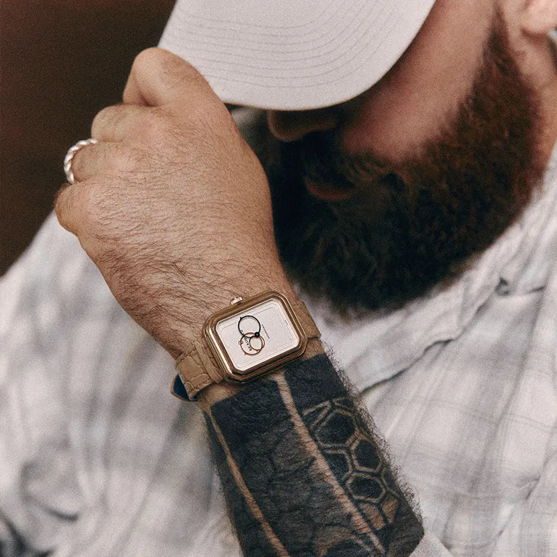 Montre Beaubleu Ecce Figura portée au poignet d'un homme avec une casquette, sur le bracelet Flat White en cuir d’alligator crème