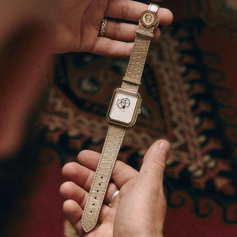 Bracelet Flat White Beaubleu et Jean Rousseau tenu entre deux mains mettant en valeur ses écailles d’alligator mixtes