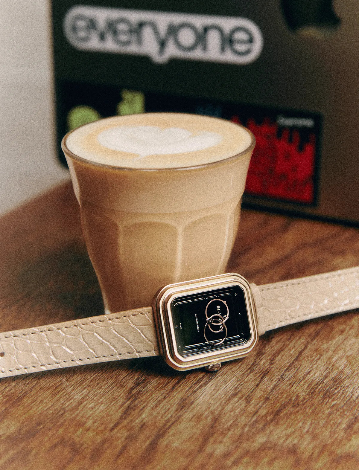 Bracelet Flat White en alligator aux écailles rondes posé devant un café Flat White.