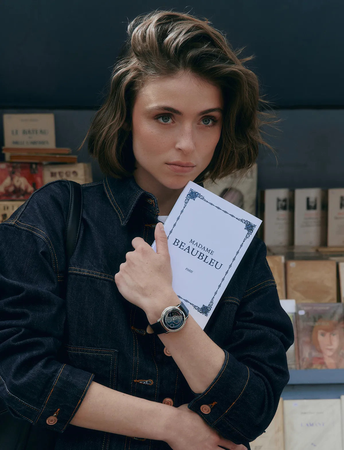 Femme tenant un livre dans la main et portant à son poignet la montre Beaubleu La Pièce Bleu Empire
