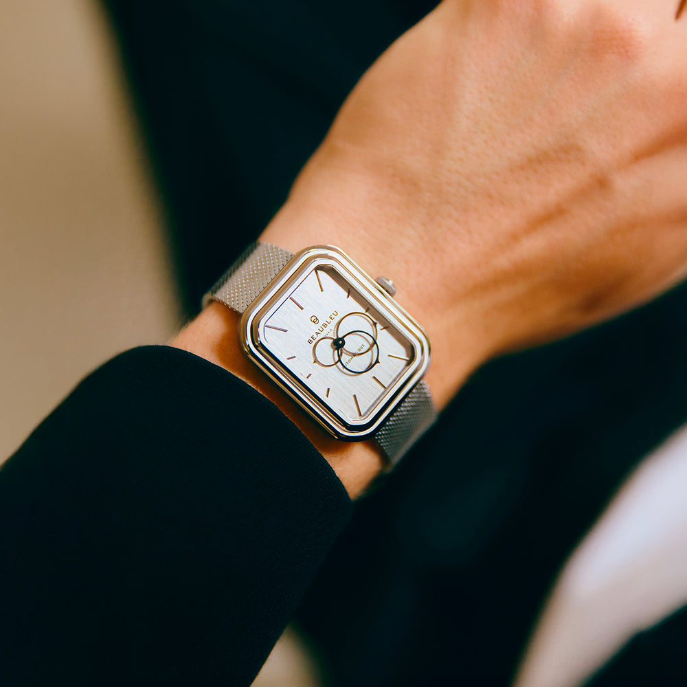 Un poignet masculin vêtu d’un costume noir portant une montre Ecce Figura avec un cadran en acier brossé