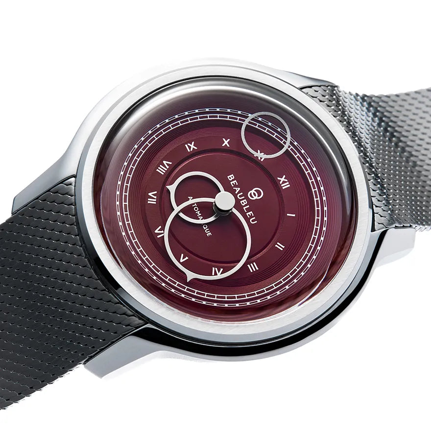 Gros plan sur une montre Beaubleu au cadran bordeaux avec bracelet en maille