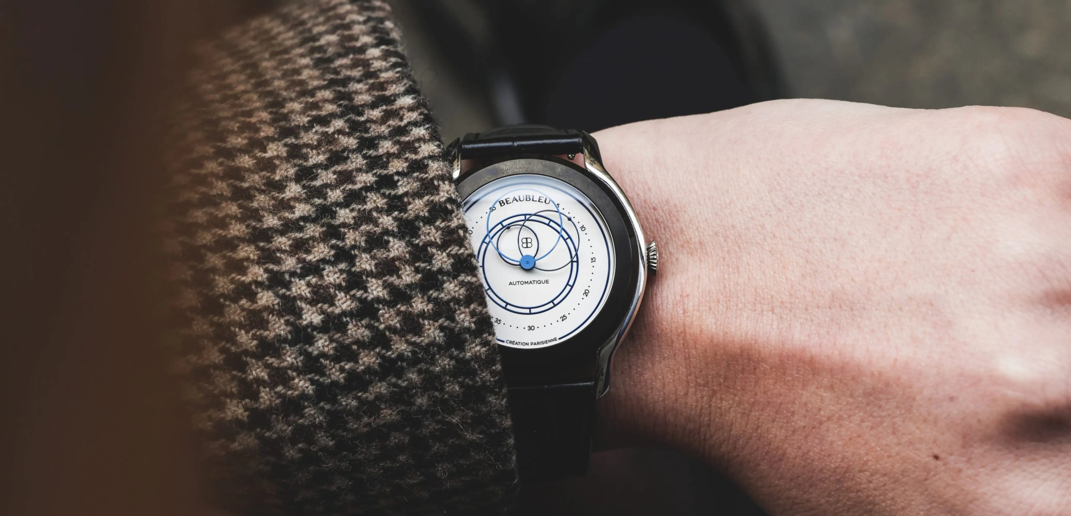 Montre Union au poignet d'un homme veste pied de poule