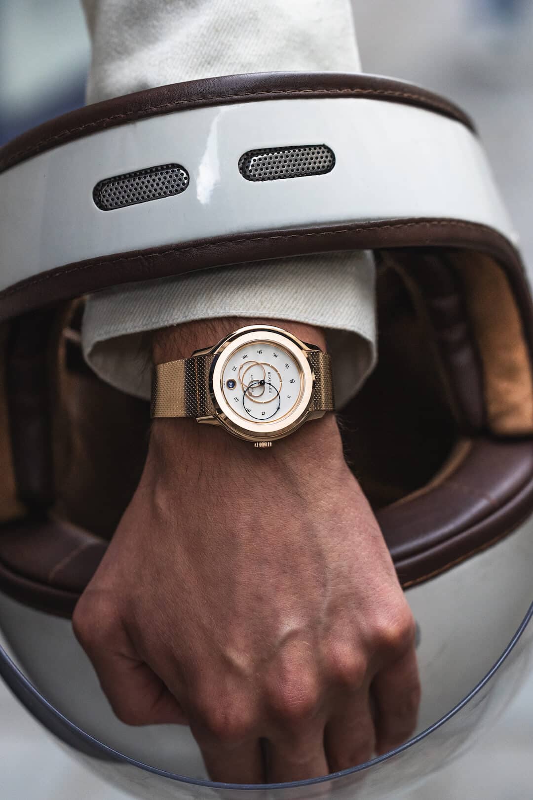 Montre Beaubleu Ecce Lys, portée au poignet d'un homme, la main passant à travers un casque de moto vintage blanc