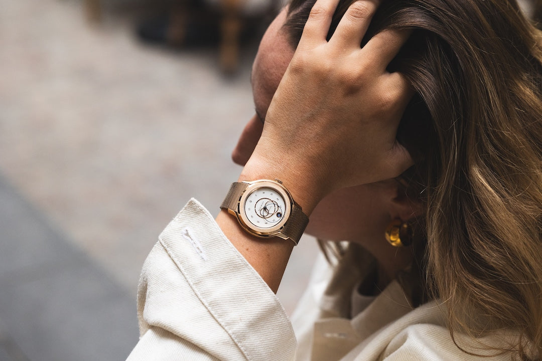 Montre Beaubleu Ecce Lys portée au poignet d'une femme, passant la main dans ses cheveux
