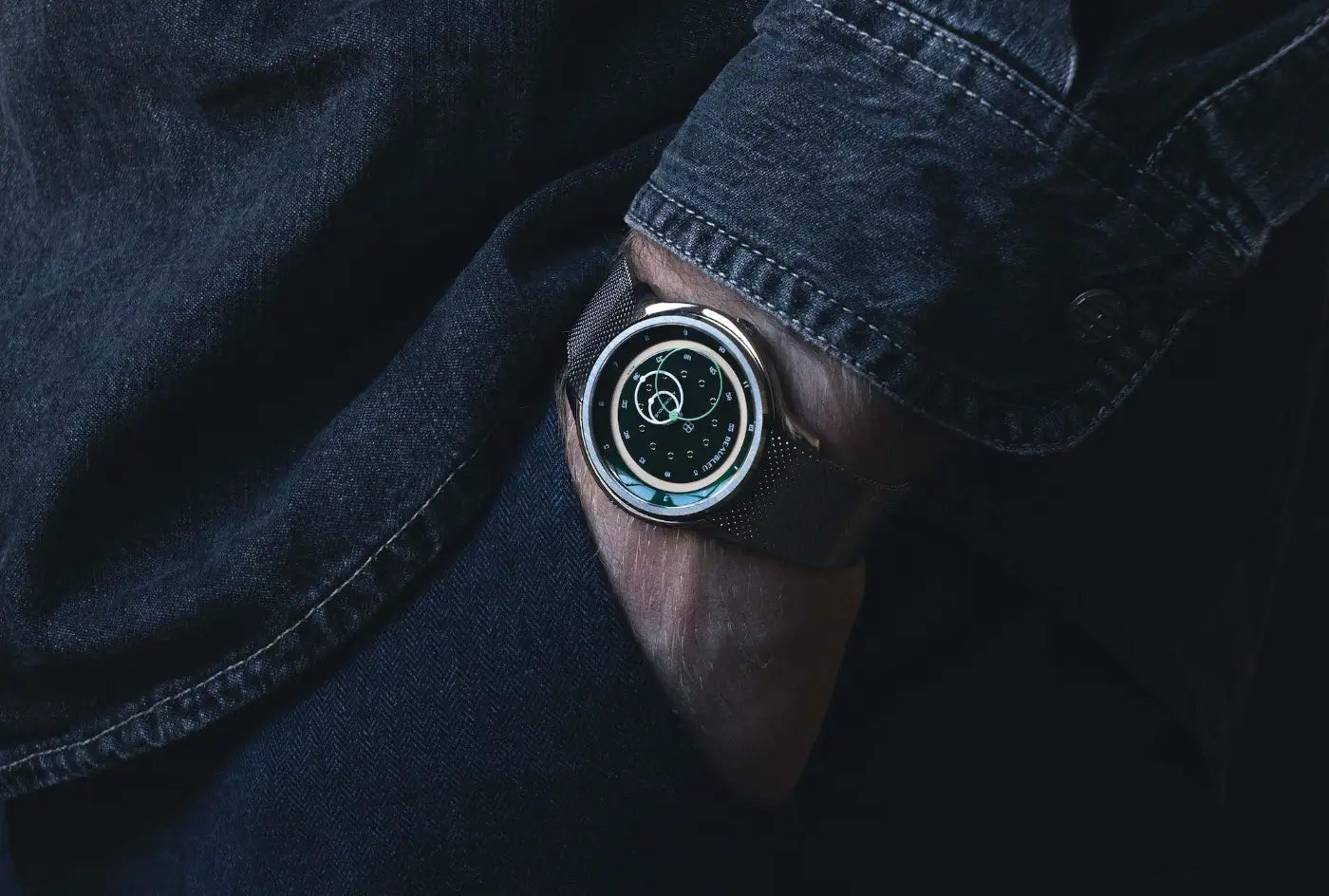 Montre GMT Green avec un bracelet en acier au poignet d'un homme, la main dans la poche de son jean