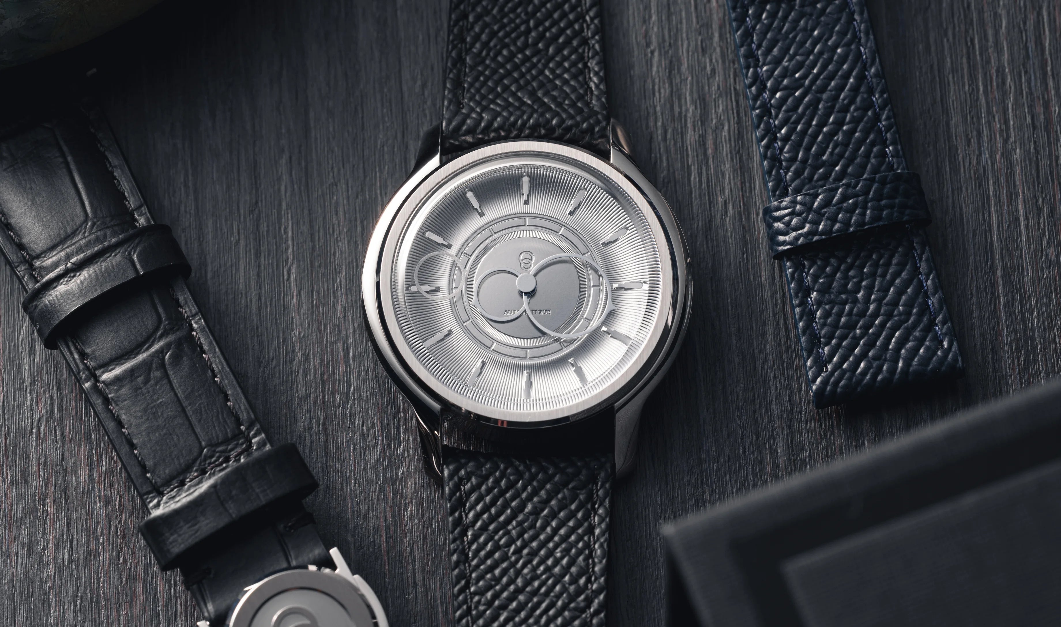 Montre La Pièce Argent de Beaubleu cadran acier posée à côté de bracelets en cuir