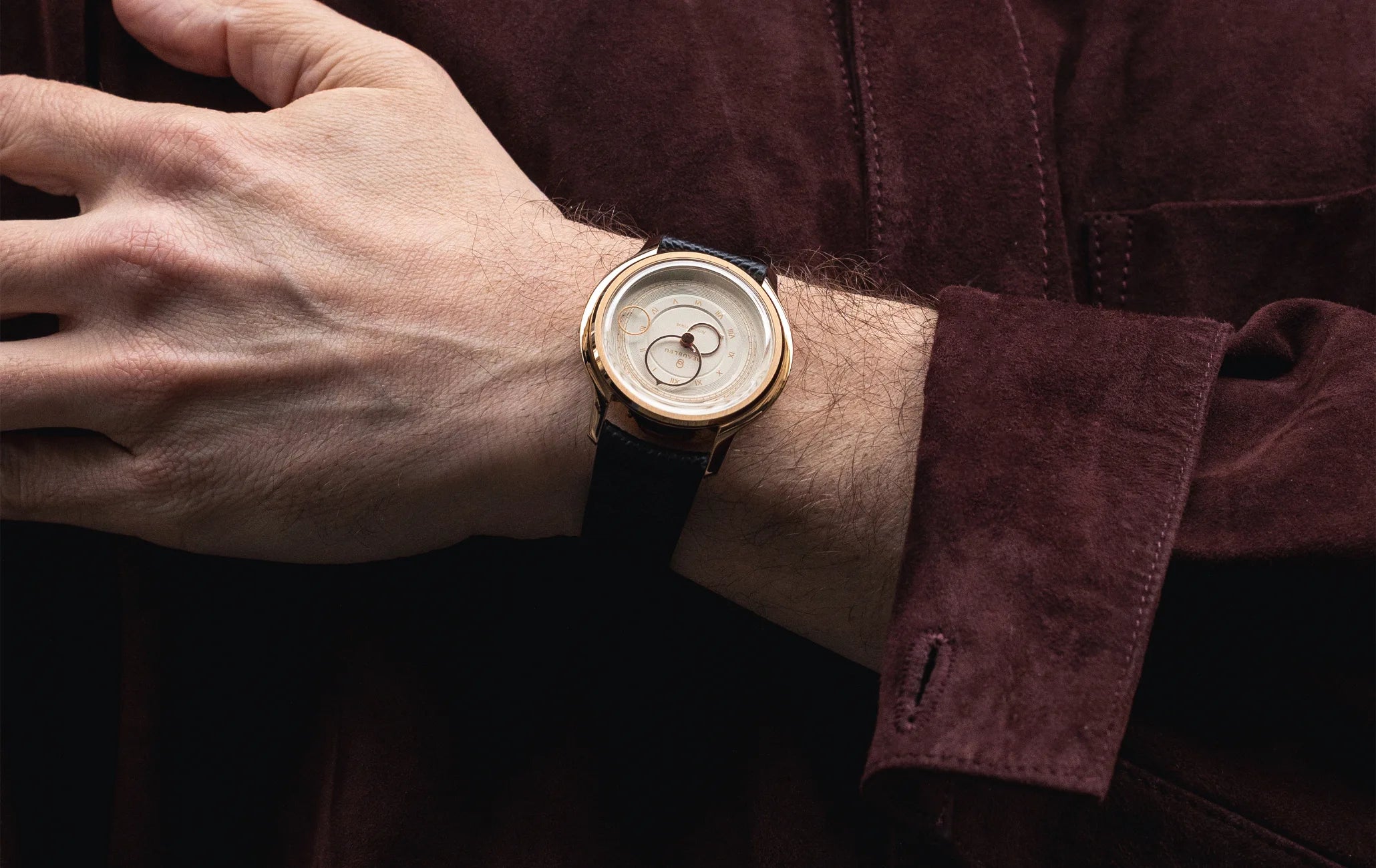 Montre Beaubleu La Pièce Champagne avec bracelet cuir grainé portée au poignet d'un homme avec une veste bordeaux