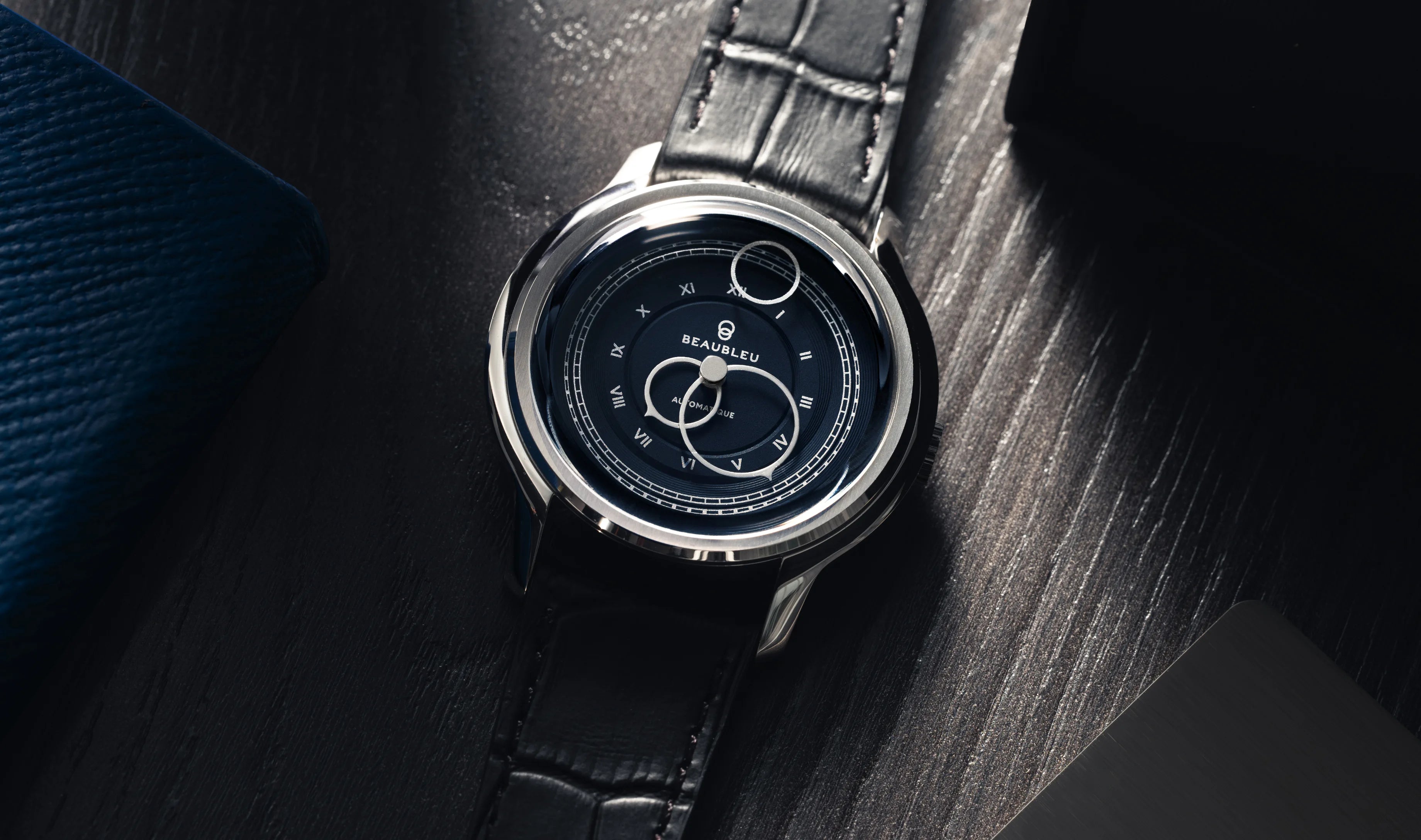 Montre La Pièce Empire de Beaubleu cadran bleu posée sur plateau avec un carnet à côté