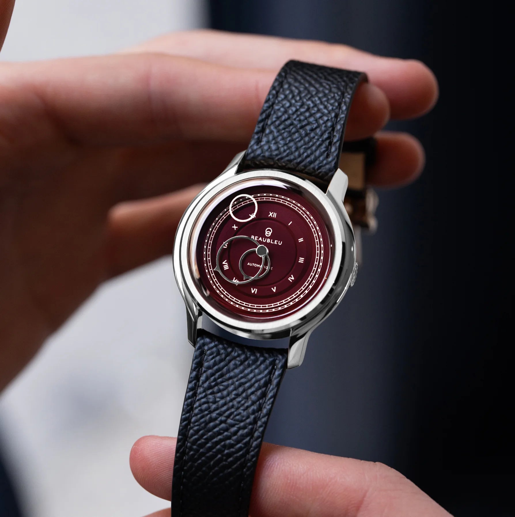 Montre La Pièce Lie de Vin de Beaubleu avec bracelet grainé tenue dans les mains