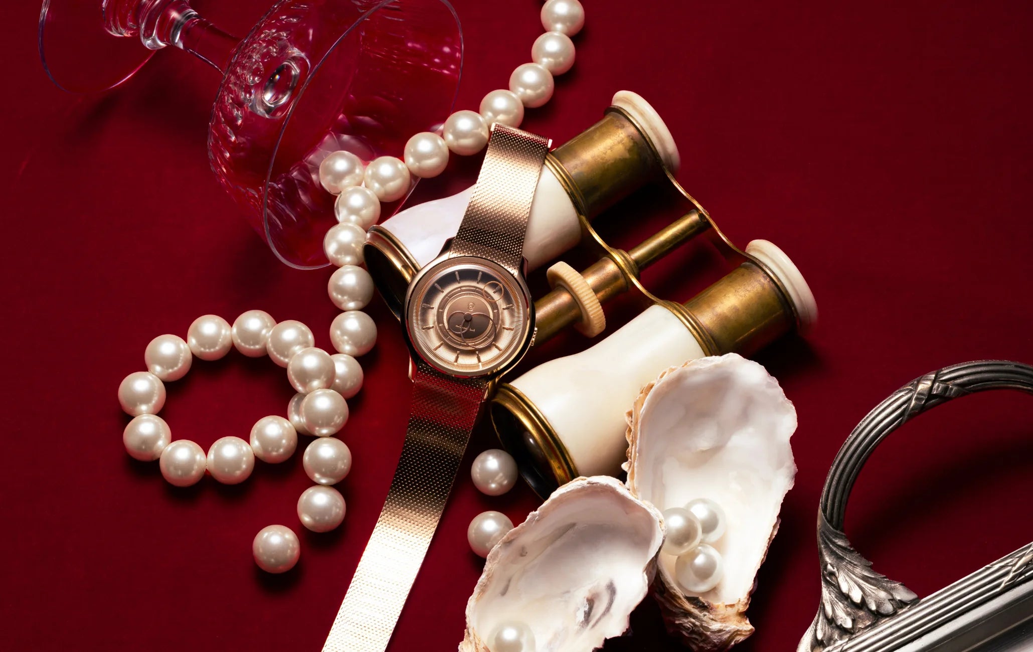 Montre La Pièce Or Rose de Beaubleu cadran or posée sur un fond rouge avec des accessoires